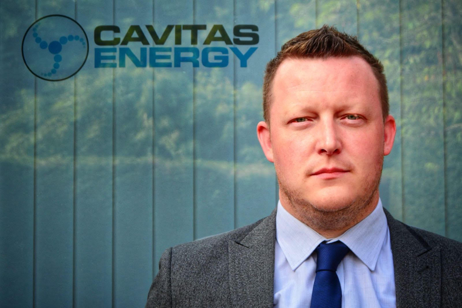 man in a suit in front of a CAVITAS ENERGY sign